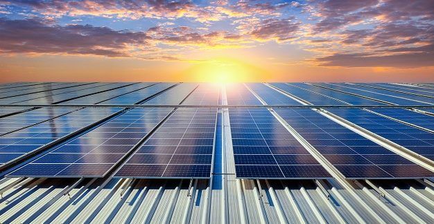 Imagen de placas solares en un tejado con el sol de fondo