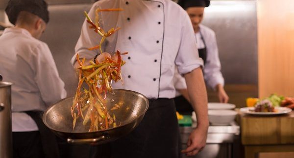 Chef moviendo wok de comida en restaurante