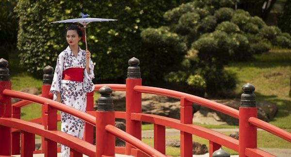Mujer vestida con traje tradicional japonés paseando por un puente representando la cultura japonesa